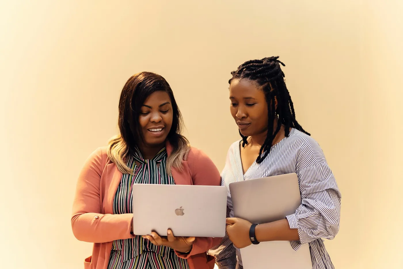 Two women reviewing work on laptops